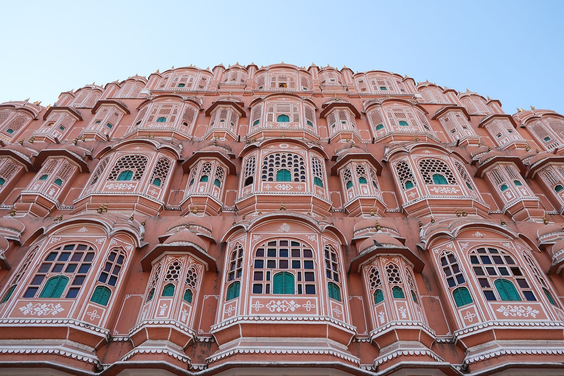 The pink sandstone façade of the Hawa Mahal in Jaipur, with tiers of small windows and jharokhas.